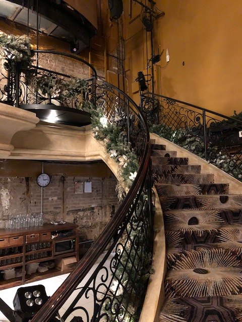 Garland with silver botanicals along a curved wrought-iron staircase